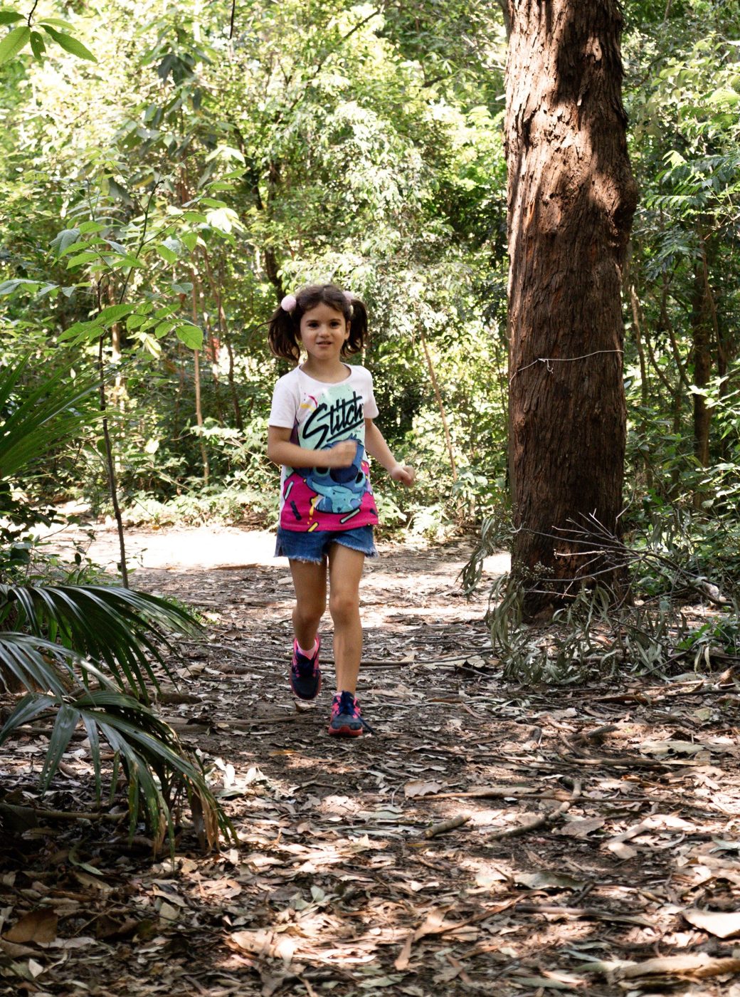 Menina correndo em trilha no meio do bosque