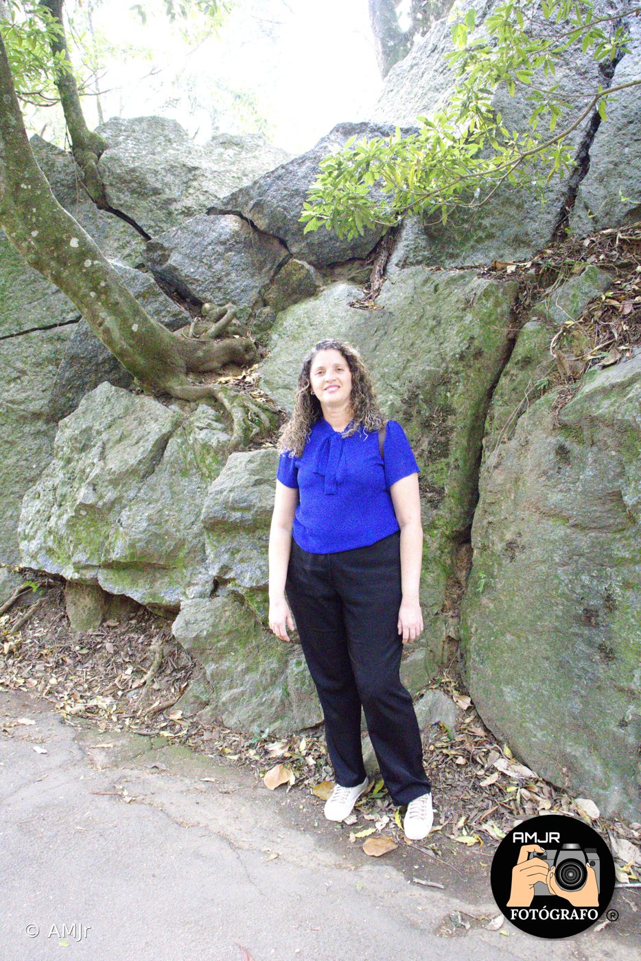 Mulher em frente a paredão de pedras com vegetação no Horto